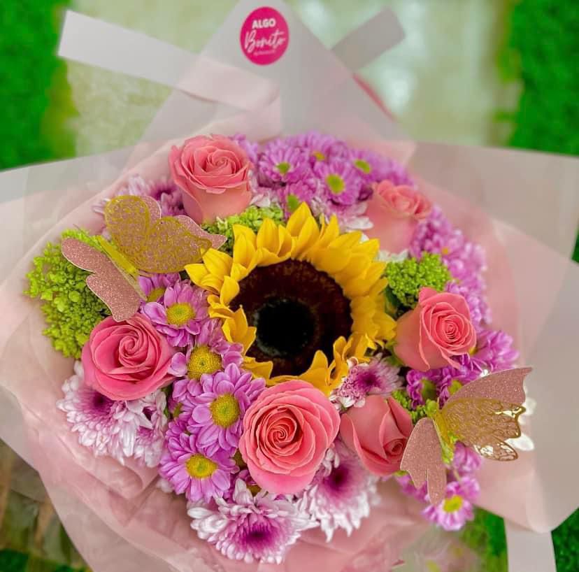 Arreglo floral con un girasol radiante y rosas rosadas